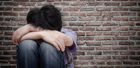 sad boy sitting on floor (iStock/parinyabinsuk)