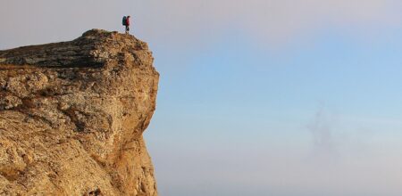 Girl hiker standing on the cliff and enjoying valley vie (iStock/aquatarkus)