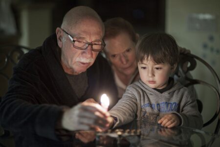 Jewish Family lighting Hanukkah Candles (iStock/Enzo Nguyen@Tercer Ojo Photography)