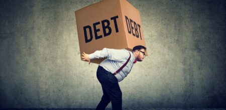 A man carrying heavy burden of debt (iStock/SIphotography)