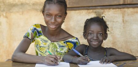 Couple of African children sitting in their desk at school (iStock/borgogniels)