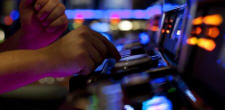 A man pressing on a button on a slot machine in casino (iStock/kmatija)