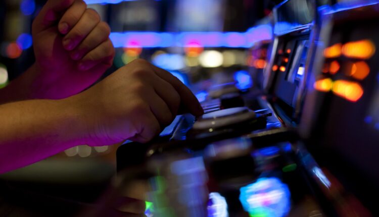 A man pressing on a button on a slot machine in casino (iStock/kmatija)