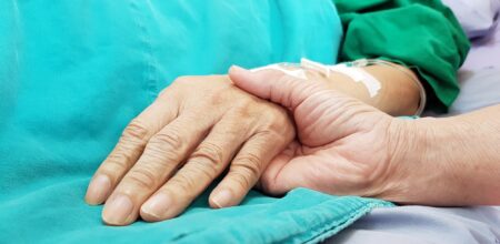 Oncologist doctor holding patient's hand in hospital. Showing all love, empathy, helping and encouragement. He has end stage cancer disease. Healthcare in end of life and palliative care concept