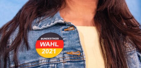 Young woman with brown hair and an election button for the German federal election on their Jeans jacket , with the inscription: "Bundestagswahl 2021" (Federal Election 2021).