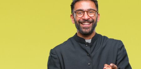 Adult hispanic catholic priest man with happy and funny face.