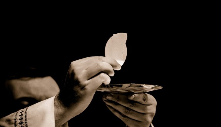 Un sacerdote sull’altare con l’ostia spezzata in mano.