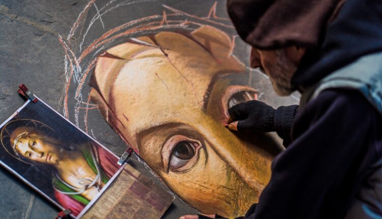 Artista di strada disegna il volto di Cristo.