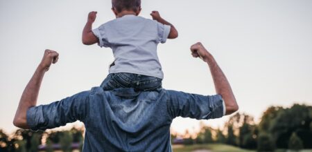 Un bimbo gioca sulle spalle del padre.